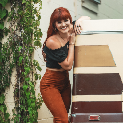Monte in orangey pants and an off-shoulder dark blouse.<br />
